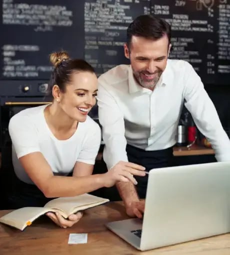 A man and woman working with a computer.